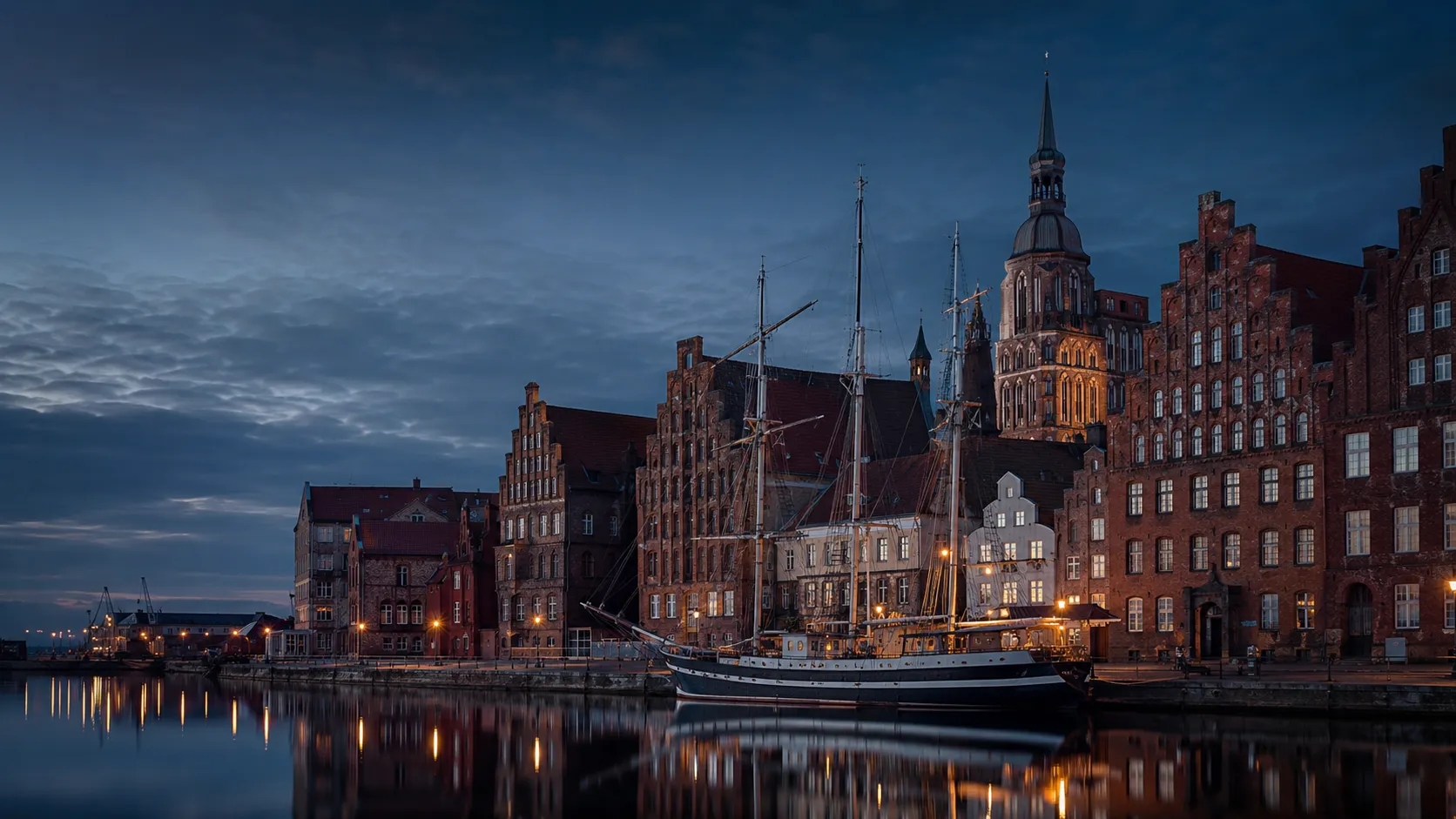 Stralsunder Hafen mit Backsteingotik und Segelschiff in der Abenddämmerung